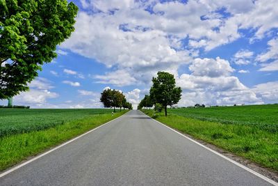 Road amidst field against sky
