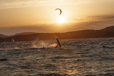 Scenic view of a kitesurfer in the sea against sky during sunset