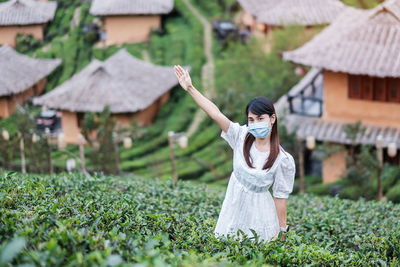 Woman with umbrella on field by house