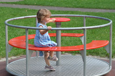 Side view of boy sitting on slide at playground