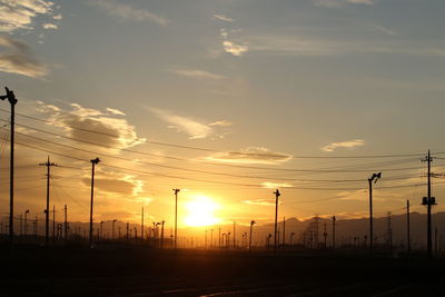 Silhouette power lines against sky during sunset