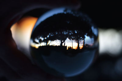 Reflection of man on mirror against sky at sunset