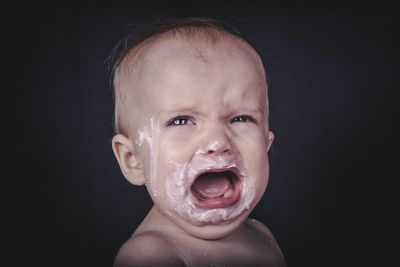 Close-up portrait of cute baby girl over black background