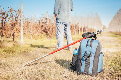 Rear view of man with bag and hiking pole on field