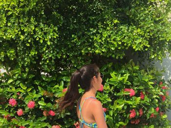 Woman standing by flowering plants in sunny day