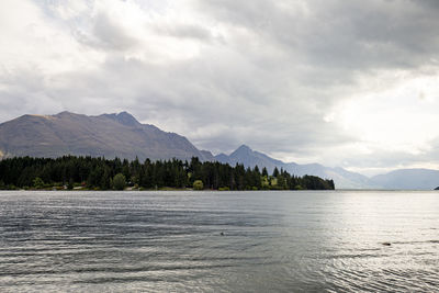 Scenic view of lake by mountains against sky