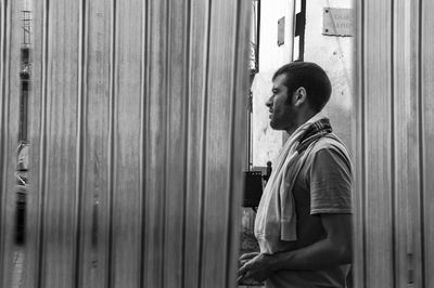 Side view of man looking away seen through curtain