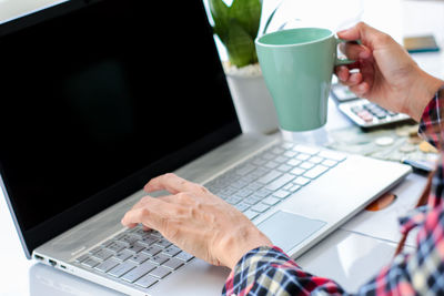 Midsection of man using mobile phone on table