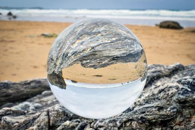 Close-up of water on rock at beach against sky