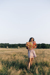 Mid adult woman holding painting while standing on grass