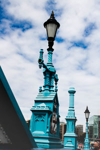 Low angle view of gas lights against cloudy sky