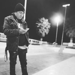 Full length of young man looking away while standing on street at night