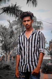 Portrait of young man standing against sky