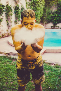 Portrait of man standing by swimming pool