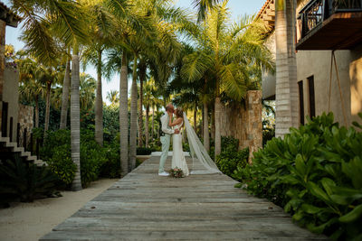 Woman walking with umbrella on palm trees