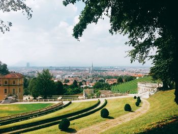 Scenic view of field by buildings against sky