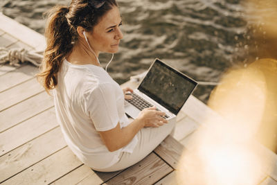 High angle view of mature woman using laptop while sitting at patio