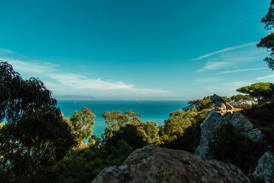 Scenic view of rocks by sea against blue sky