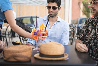 Midsection of woman serving drinks to male customer at outdoor cafe