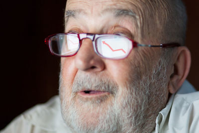 Senior man wearing eyeglasses with reflection of graph