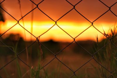 Chainlink fence against sky during sunset