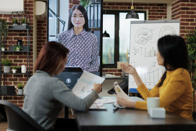 Portrait of young woman using mobile phone while sitting at office