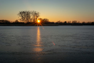 Scenic view of frozen lake against sky during sunset