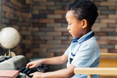 Side view of boy using typewriter