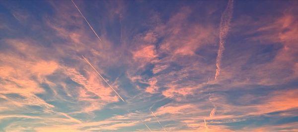 Low angle view of vapor trail in sky during sunset