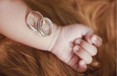 Dad and mom wedding rings on their baby