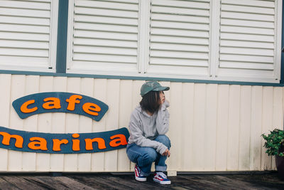 Full length of boy sitting against wall