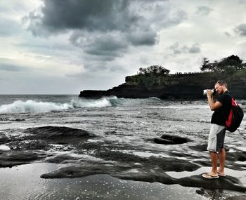 Woman photographing sea against sky