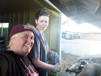 Portrait of mature woman with friend by car at garage