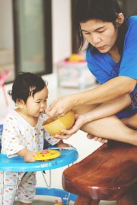 Mother feeding daughter at home