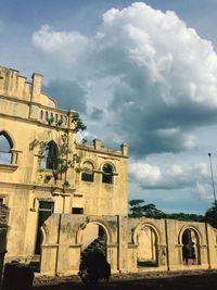 Low angle view of old building against cloudy sky