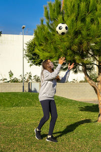 Full length of girl wearing mask playing with soccer ball in park