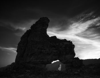 Low angle view of rock formation against cloudy sky