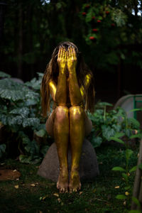 Young woman with golden skin sitting in the garden