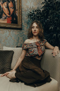Portrait of young woman sitting on sofa at home