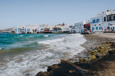 Buildings by sea against clear sky