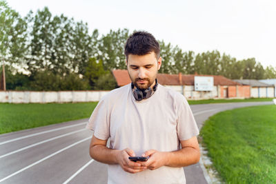 Young man using mobile phone while standing on field