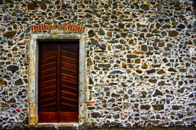 Closed vintage wooden door on ancient stone wall in mare di lugo, vicenza, italy