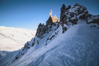 Low angle view of snow mountains against clear blue sky