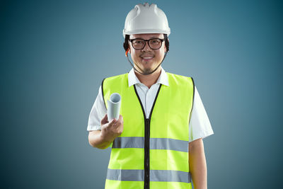 Portrait of worker in reflective clothing standing against wall
