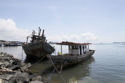 Ship moored at harbor against sky