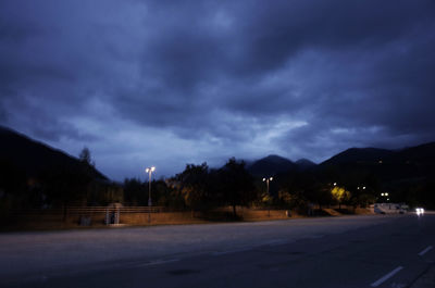 Empty road against cloudy sky at night