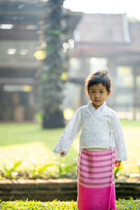 Girl standing on grass against building