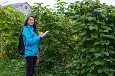 Portrait of young woman standing against plants