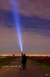 Silhouette woman standing on road against sky at sunset