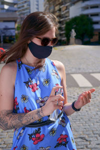 Young woman wearing sunglasses standing on street in city